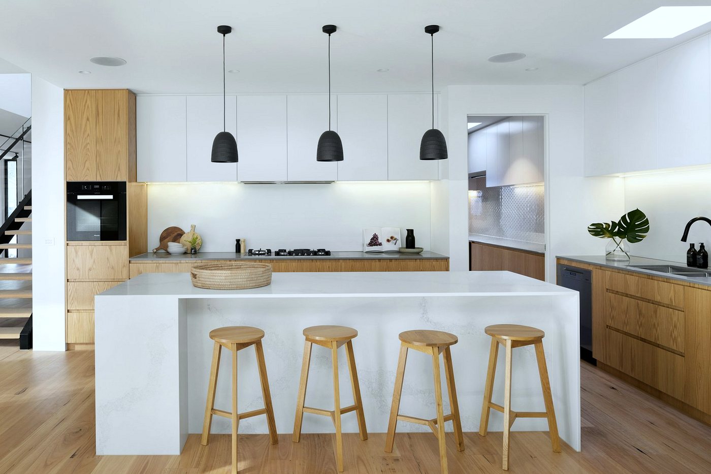 Newly fitted kitchen with oak and white units, a white island worktop and wood flooring
